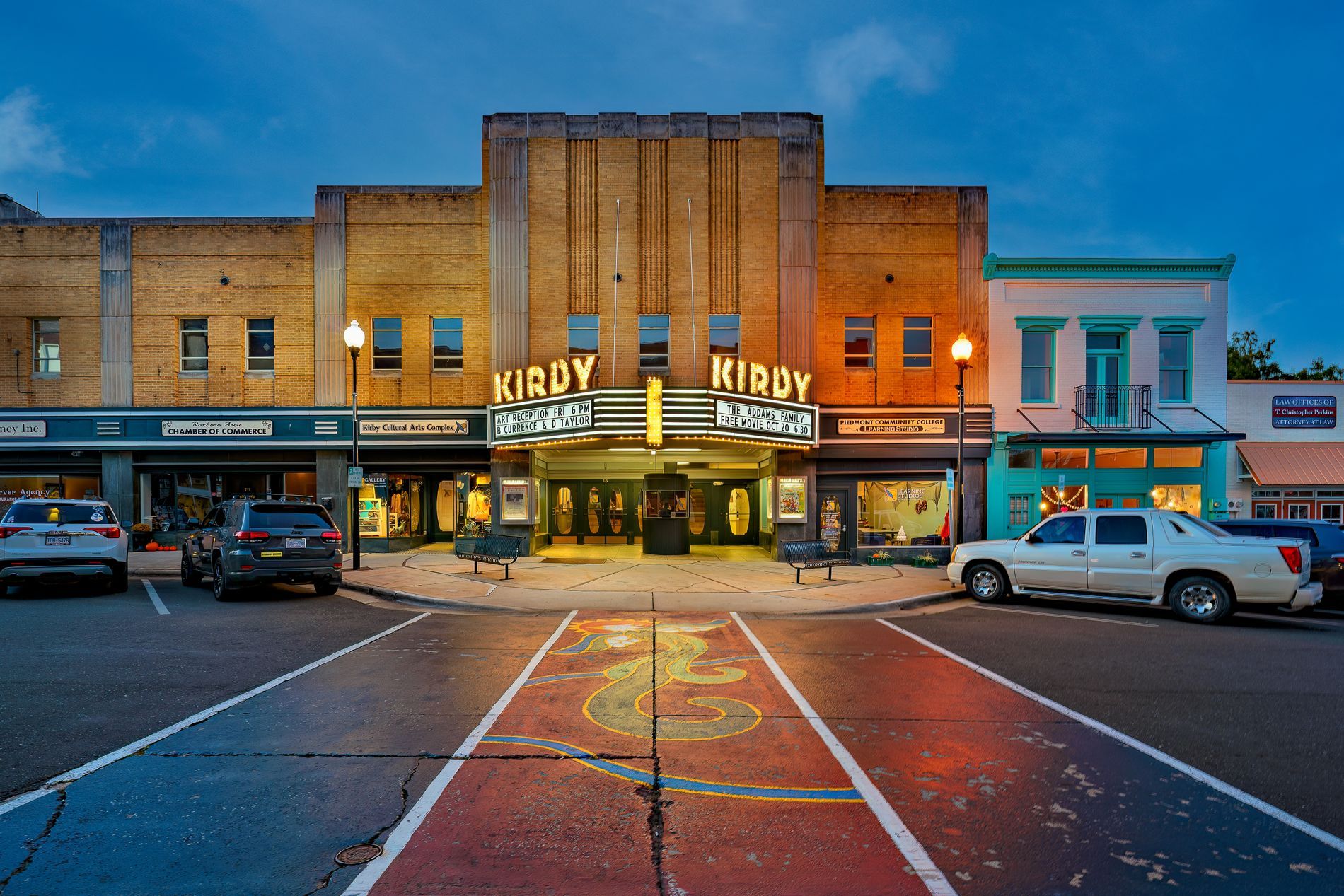 An art-deco theater on a small-town main street at dusk