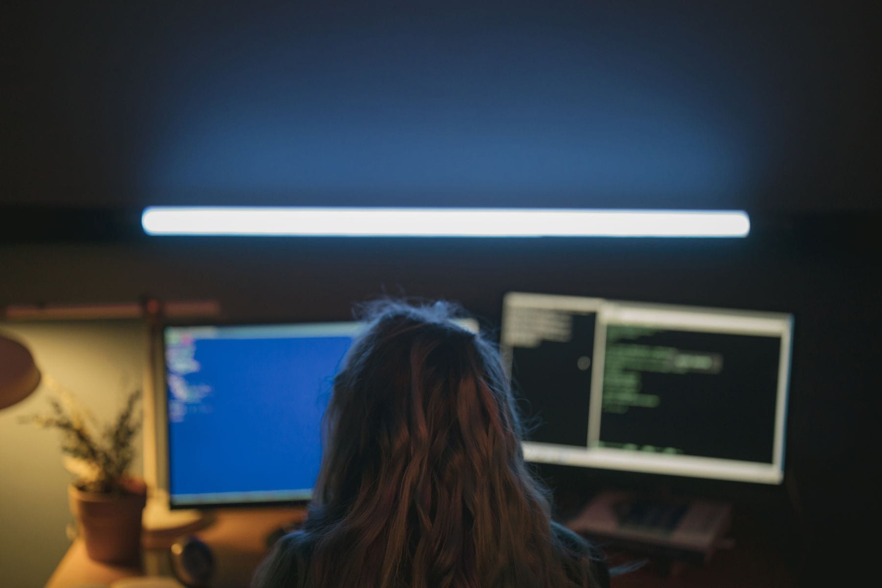 Developer at glowing screens in a dark studio