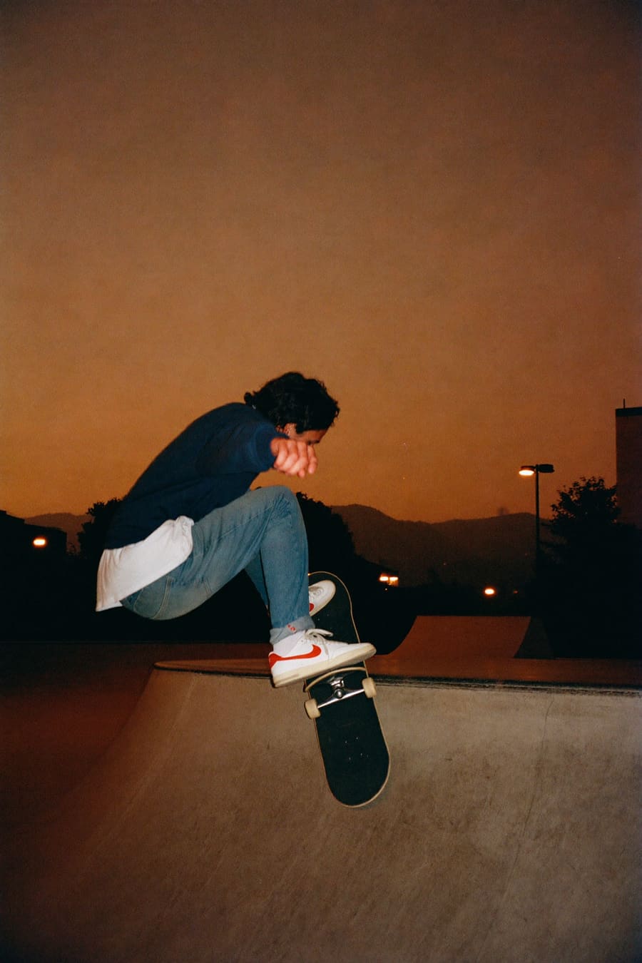 Skater dropping into a concrete bowl at dusk