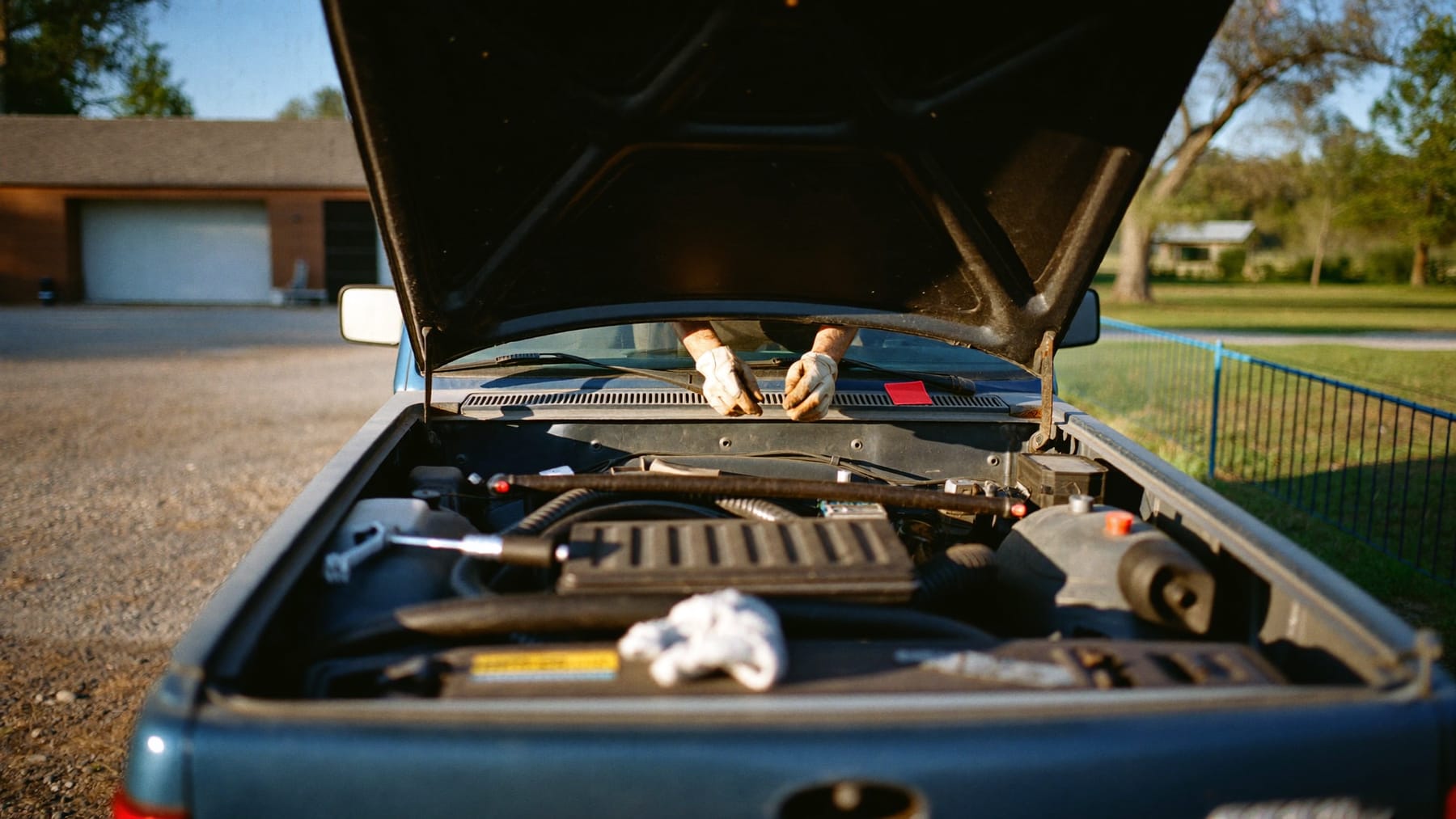 Mechanic working under the hood of a diesel pickup at golden hour