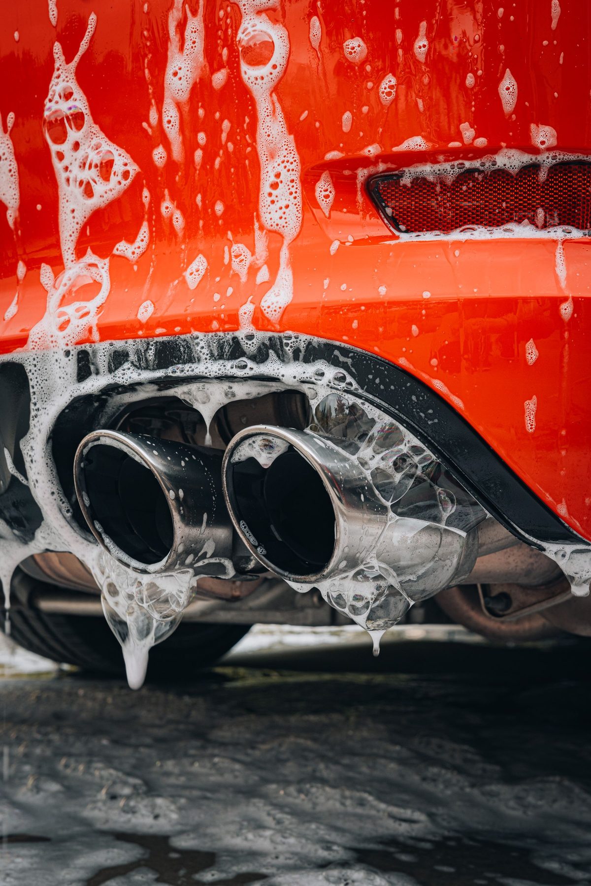Foam wash over a red car's exhaust